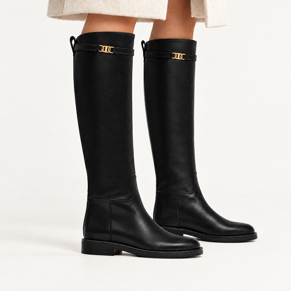 Harlow black knee high riding boots worn with a cream wool coat